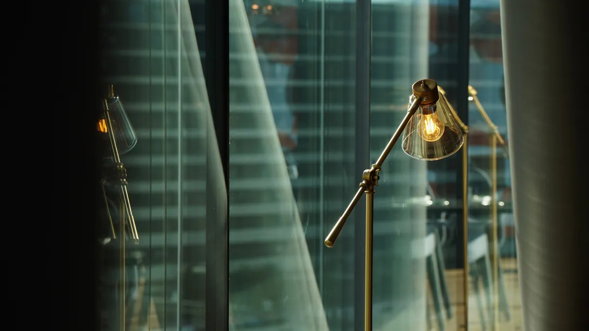 Lampe en laiton allumée devant une baie vitrée