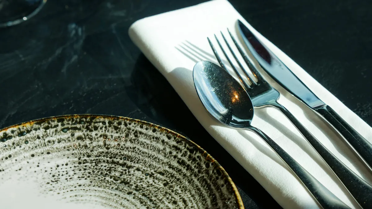 Couverts sur une serviette blanche, assiette en céramique mouchetée