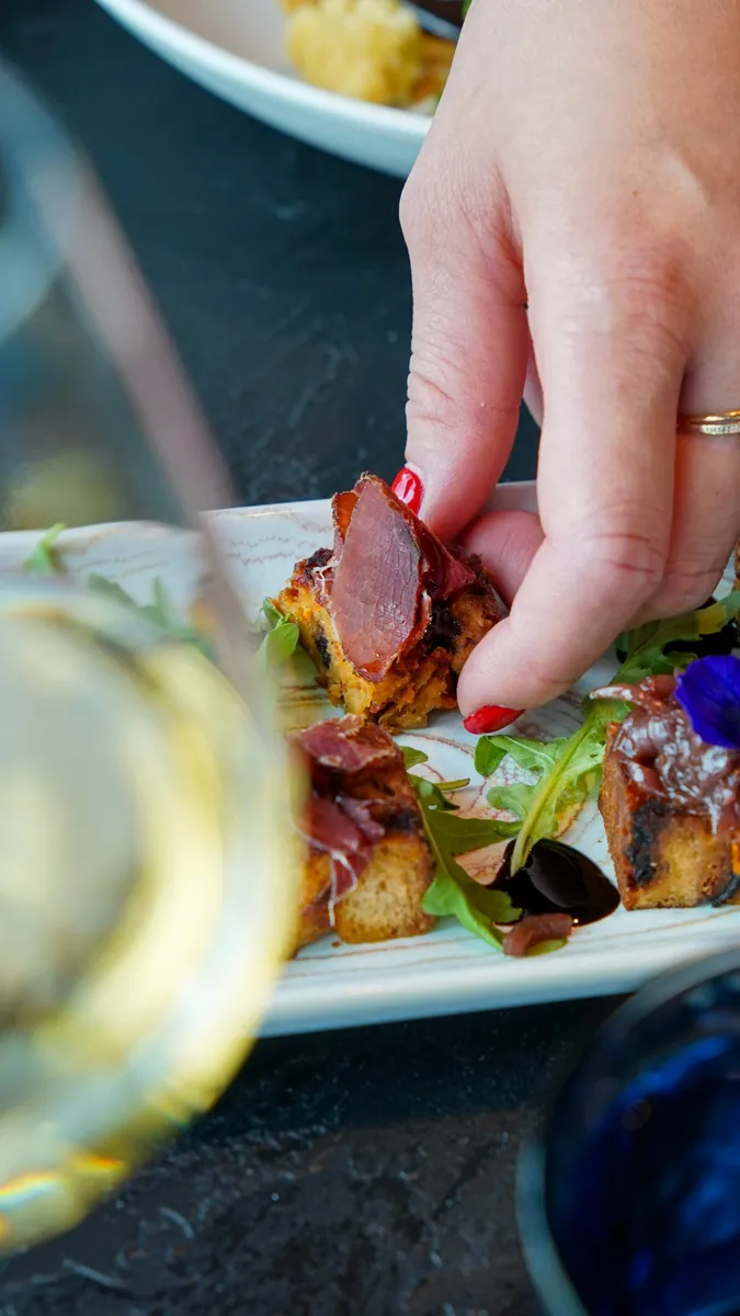 Main saisissant un toast garni de viande séchée